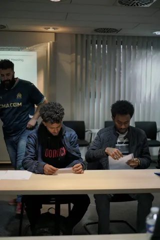 Two participants reading the handouts at the Get Your Home workshop while a third person leans in behind them