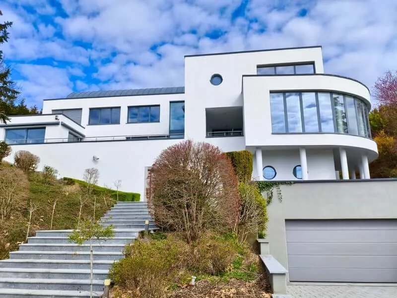A YWS shared house in Luxembourg: a modern white villa with wide windows above garden steps